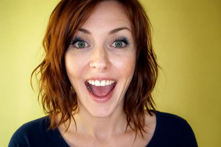 Mulher com expressão facial intensa e sorriso aberto, ilustrando como expressões faciais fingidas podem parecer convincentes sem comprovar uma emoção real.